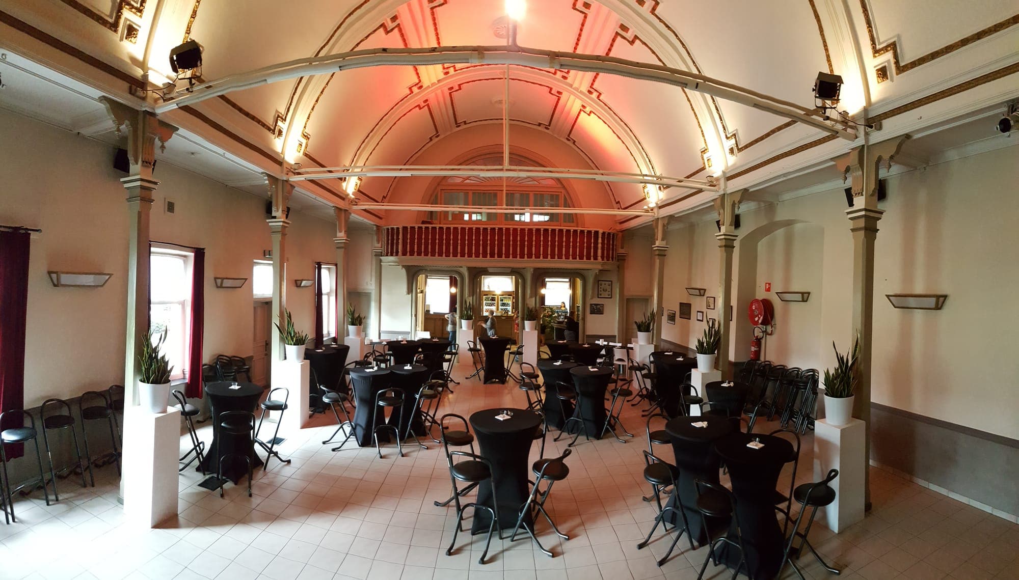 De feestzaal met gewelfd plafond, staantafels en de bar